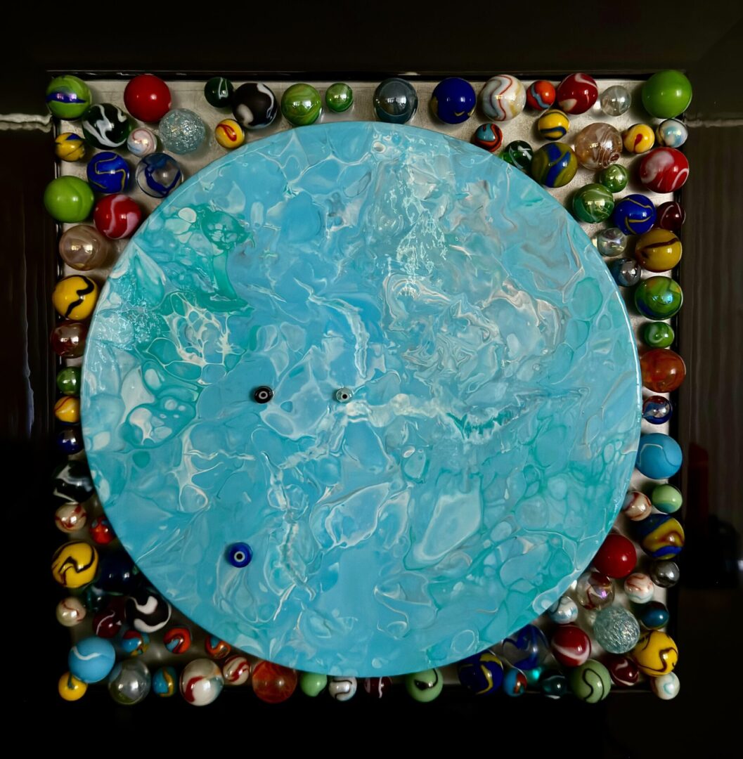 A blue circle with many different colored marbles around it.