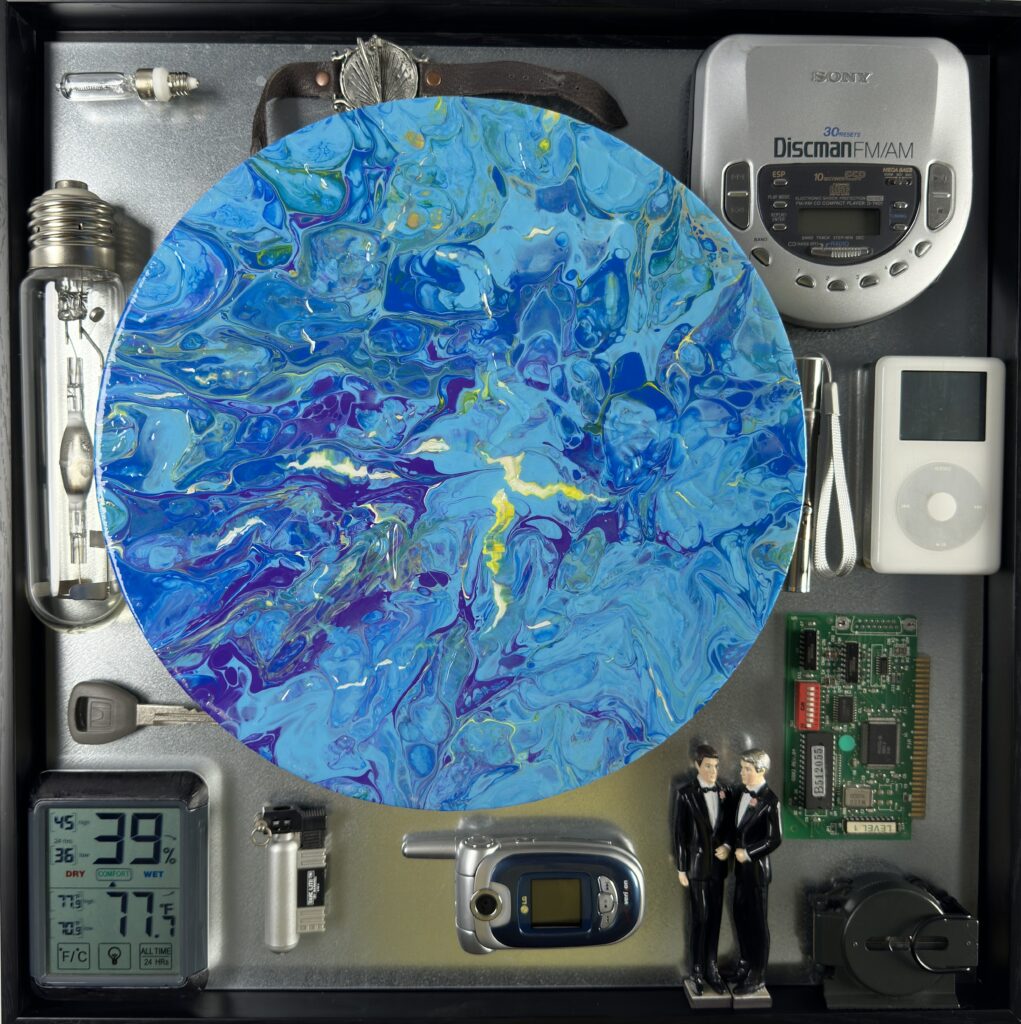 A blue painting surrounded by electronic devices and other items.